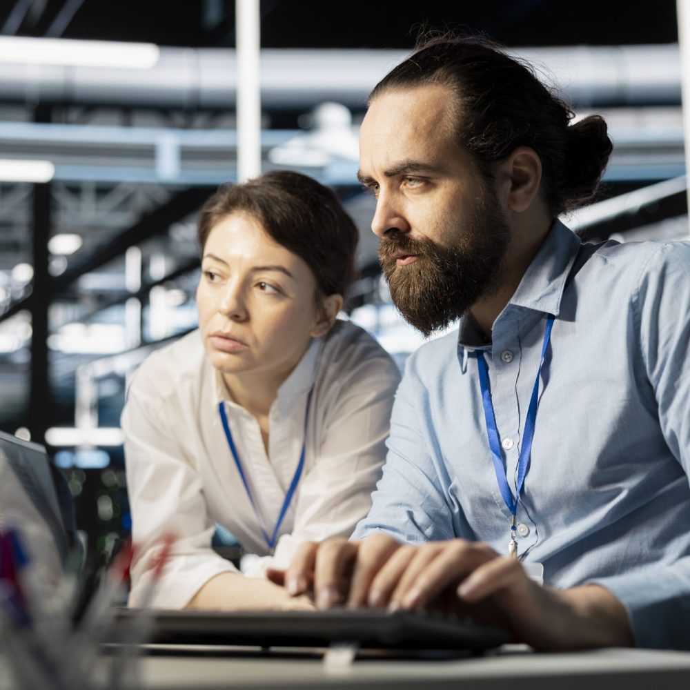 Data center coworkers doing brainstorming, running diagnostic scripts on computer, examining hardware. Server room employees talking, working together to evaluate performance metrics